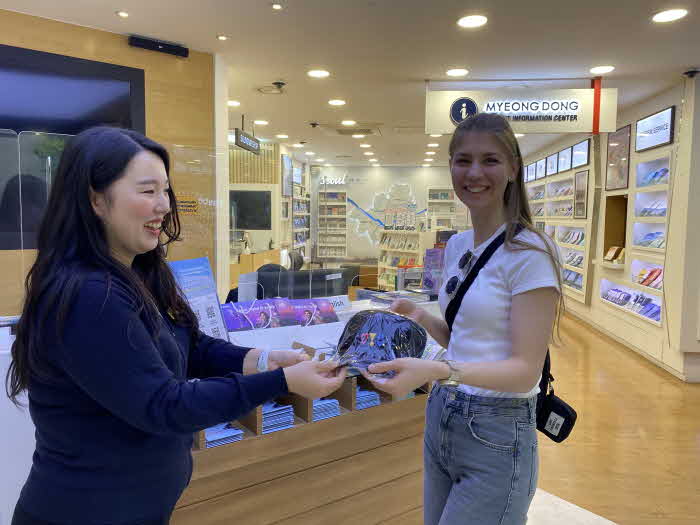 (사진1) 명동관광정보센터에 방문한 독일인 관광객이 비짓서울 이벤트 참여 후 서울굿즈 기념품을 받고 있다..jpg